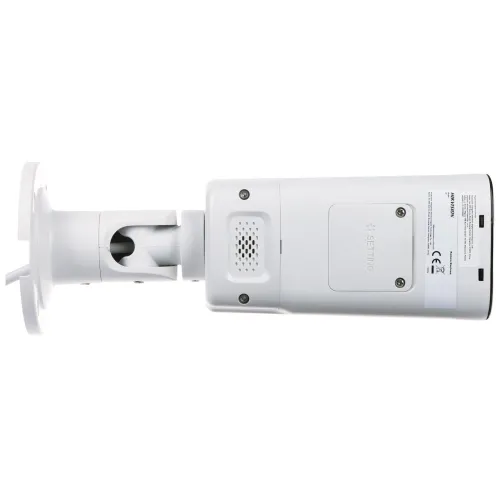 Biała kamera monitoringu z prostokątną obudową i regulowanym uchwytem montażowym. Na obudowie widoczne są otwory wentylacyjne oraz etykieta z informacjami technicznymi.