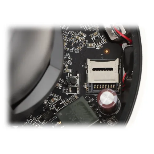 Wnętrze kamery z widocznym gniazdem na kartę micro SD oraz elementami elektronicznymi na płytce drukowanej. Obok gniazda znajdują się różne komponenty, takie jak kondensatory i przewody.