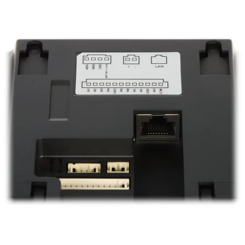Zdjęcie przedstawia panel złącz elektronicznych, w tym port LAN oraz różne złącza pinowe. Panel jest czarny z oznaczeniami opisującymi funkcje poszczególnych złącz.